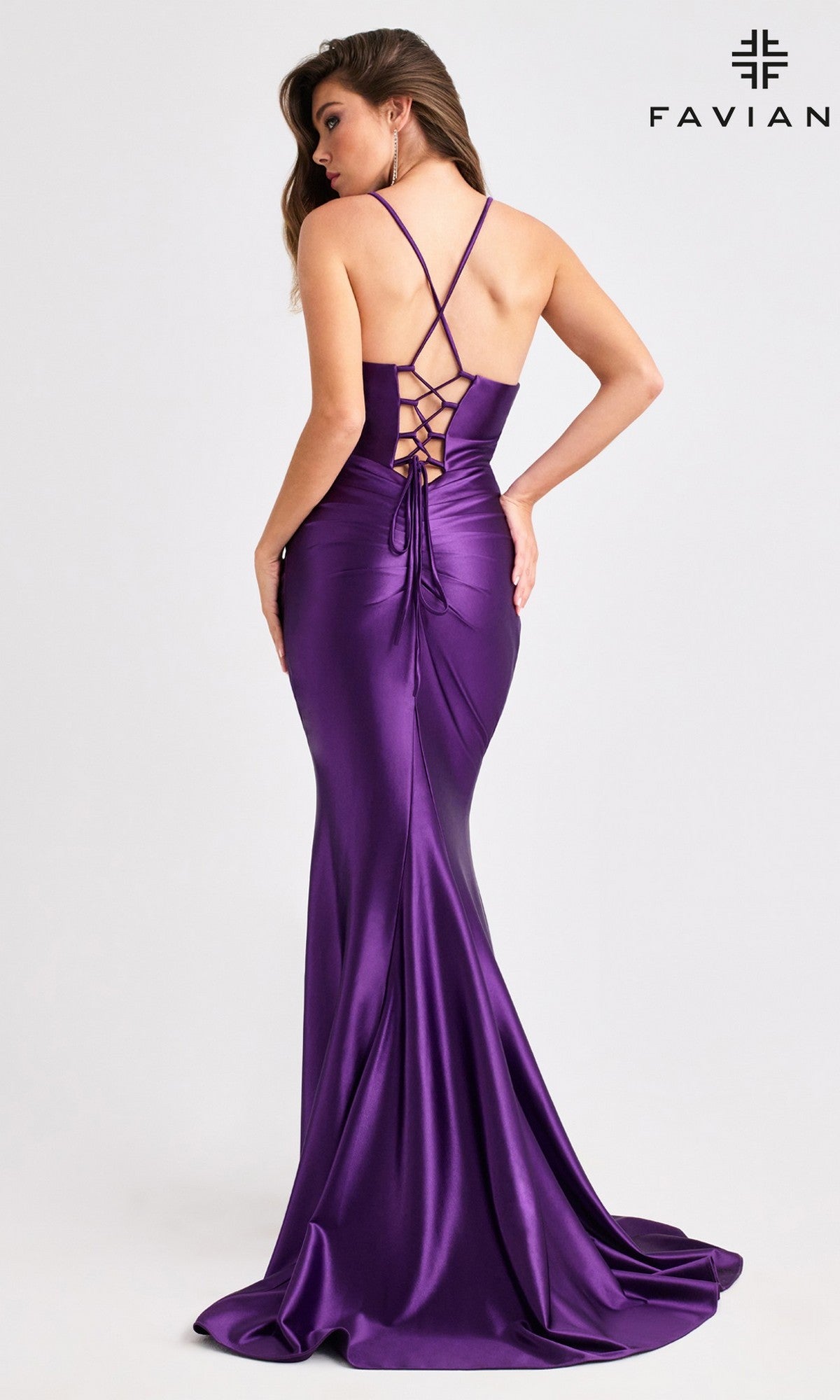A woman models the Faviana E11423 long purple satin prom dress with a lace-up open back, crisscross straps, and a leg slit, standing against a plain background.